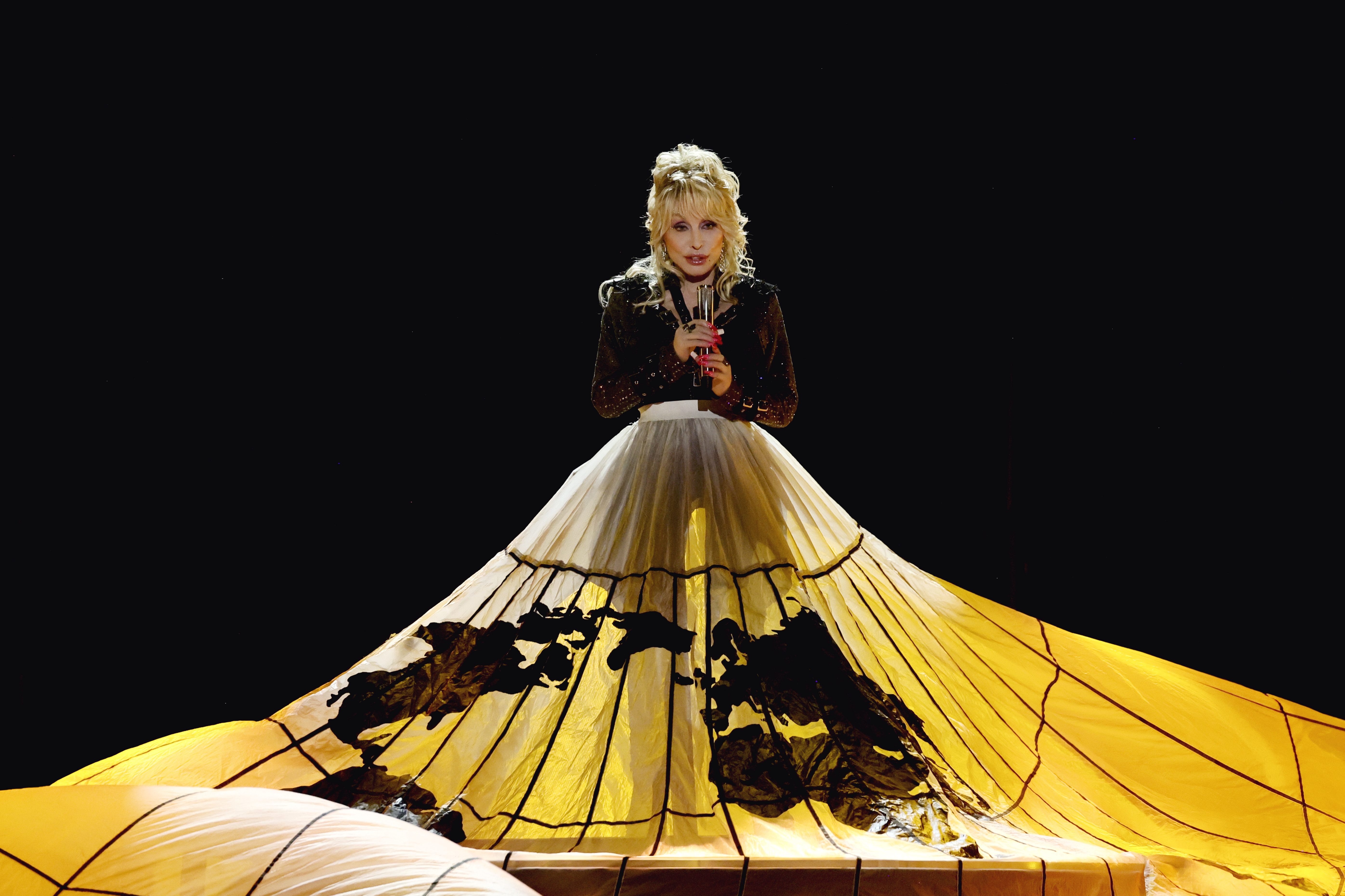 Dolly Parton performing in a dramatic gold gown